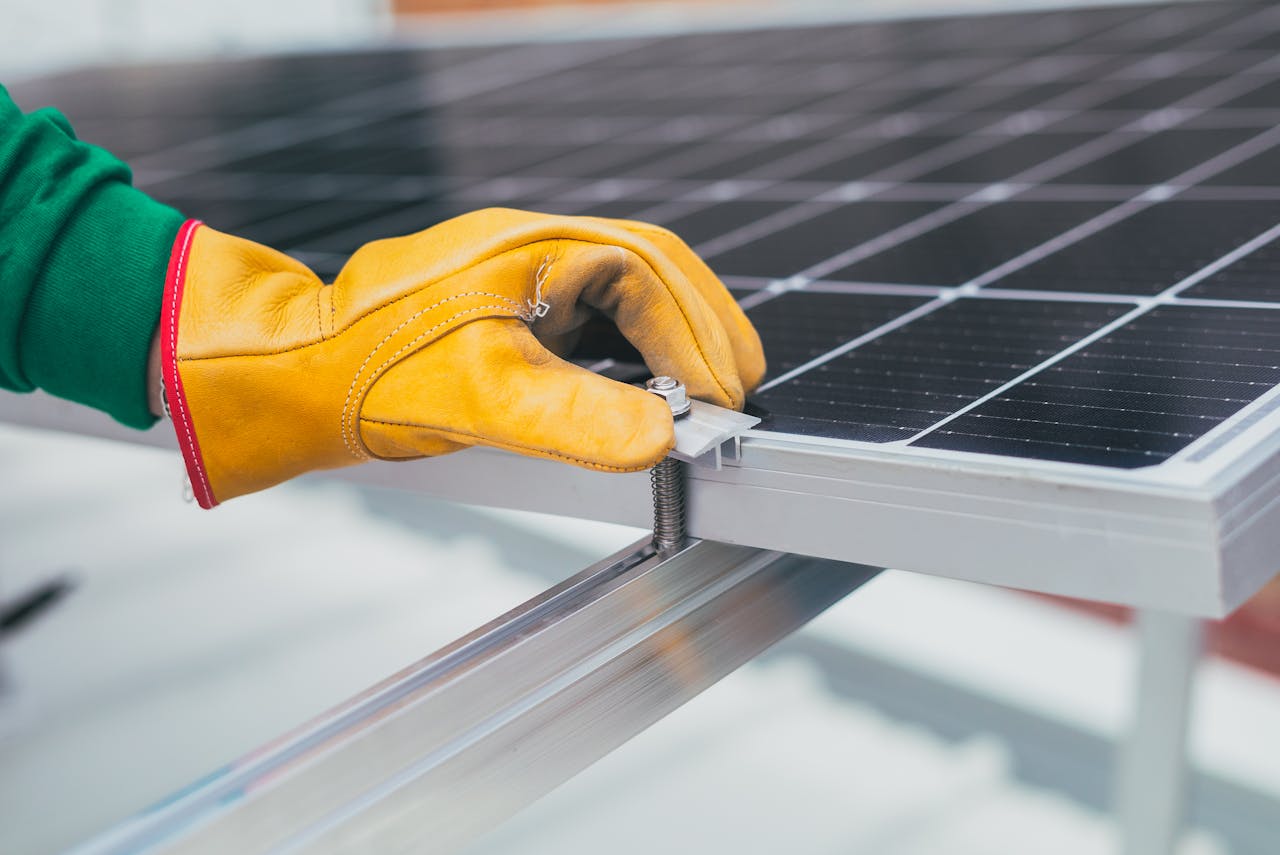 Main gantée serrant une fixation de panneau solaire sur une structure en aluminium