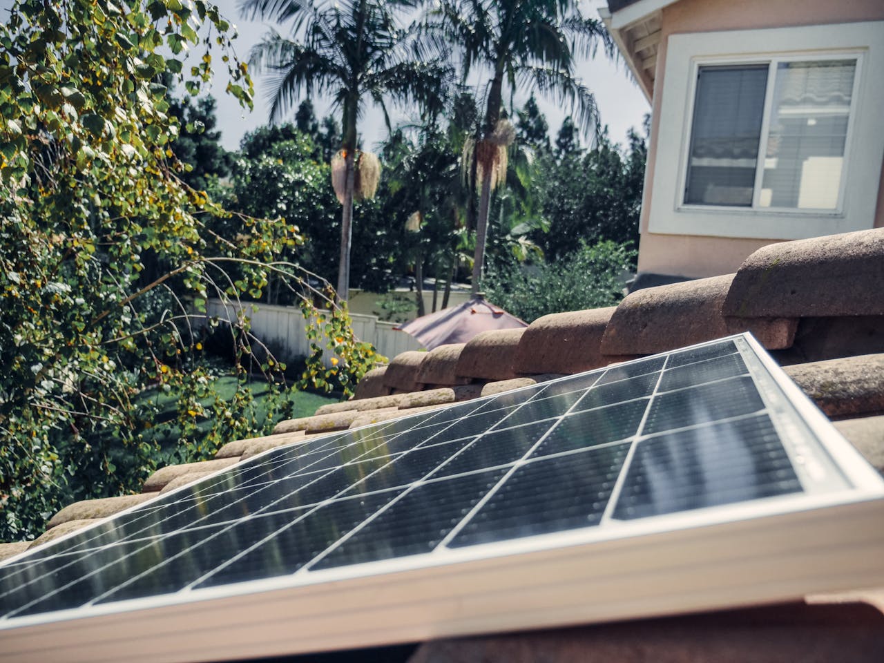 Panneau solaire installé sur un toit en tuiles, exposé au soleil dans un jardin arboré